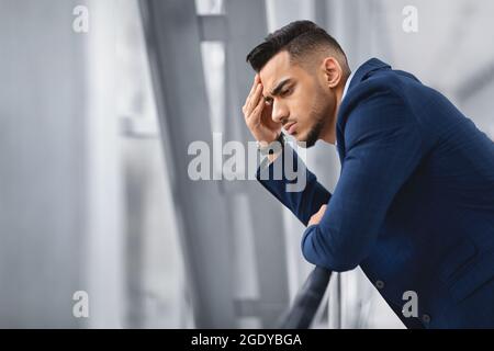 Portrait d'un homme pensif du Moyen-Orient debout près de la fenêtre au terminal de l'aéroport