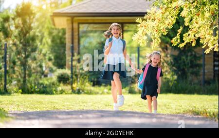 Élèves de l'école primaire. Filles avec sacs à dos à l'extérieur. Début des leçons. Premier jour de l'automne. Banque D'Images