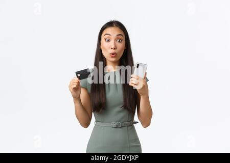 Propriétaires de petites entreprises, femmes entrepreneurs concept. Surprise et excitée asiatique d'achat en ligne, regardant impressionné par les réductions tout en tenant Banque D'Images