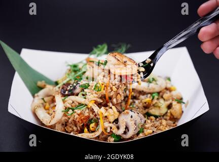 Riz frit aux fruits de mer préparés au wok. Restauration rapide chinoise saine. Crevettes, calmars et pieuvre avec riz sautés au wok, légumes chinois comme concept alimentaire végétarien. Image de haute qualité Banque D'Images