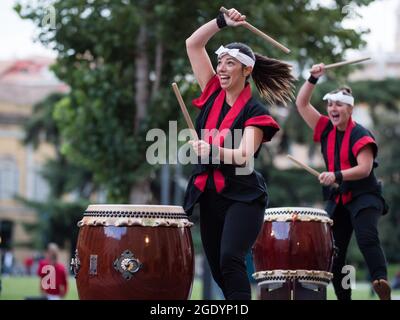 Fille jouant des tambours de la tradition musicale japonaise lors d'un événement public en plein air. Banque D'Images