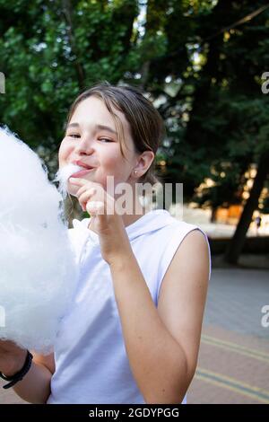 une adolescente mange des bonbons en coton dans un parc d'attractions. Banque D'Images