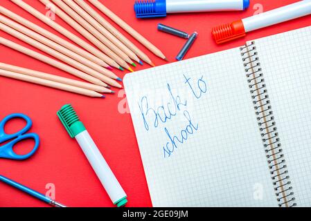 Retour à l'école. L'enfant écrit dans un carnet avec un stylo plume le concept du début de l'année scolaire. Bannière pour le site sur un rouge Banque D'Images