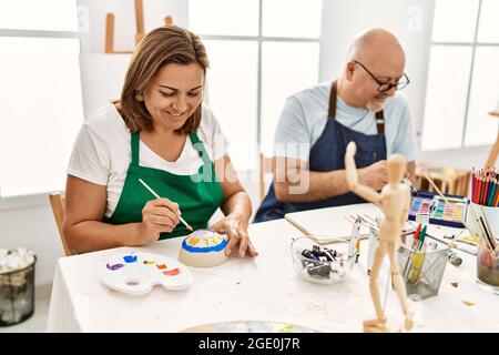 Le peintre hispanique d'âge moyen couple souriant Happy Painting au studio d'art. Banque D'Images