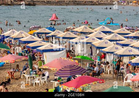Vue en grand angle des familles sous les parasols de la plage s'amuser, temps de baignade, Skikda, Algérie. Banque D'Images