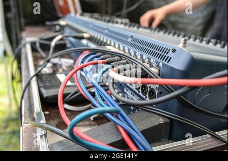 Câbles de microphone rouge et bleu connectés dans une console de mixage sonore au niveau du contrôle sonore pour un festival de musique en plein air, une mise au point sélectionnée, une profondeur de f étroite Banque D'Images