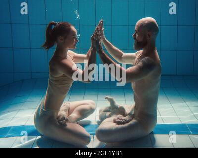 portrait sous l'eau de l'atlethique, la danse sportive et faisant le yoga asanas couple (homme et femme) sous l'eau dans la piscine Banque D'Images