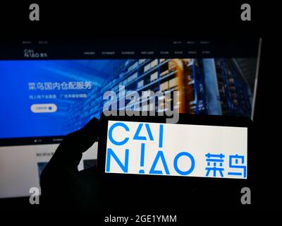 Personne tenant un smartphone avec le logo de la société Cainiao Smart Logistics Network Limited à l'écran devant le site Web. Mise au point sur l'affichage du téléphone. Banque D'Images