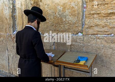 Juif orthodoxe en tenue noire traditionnelle priant au mur des Lailing (alias Kotel) - ancien mur dans la vieille ville de Jérusalem, Israël. Banque D'Images