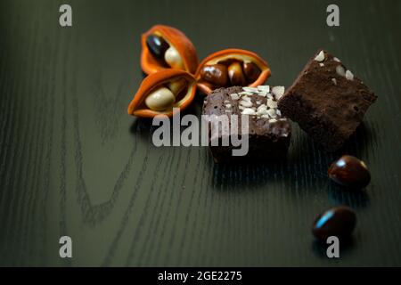 Gros plan de chocolats et de fruits sterculia avec une peau rouge et orange sur une surface en bois Banque D'Images