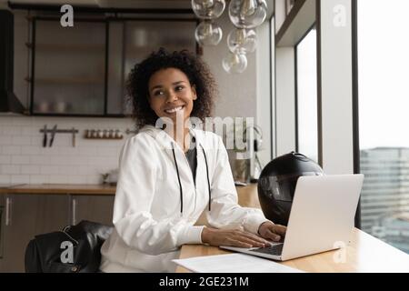 Femme africaine souriante assis à table sourit les yeux de côté Banque D'Images