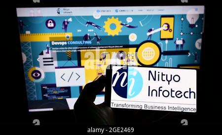 Personne tenant un smartphone avec le logo de la société américaine Nityo Infotech Services Pvt. Ltd. À l'écran devant le site Web. Mise au point sur l'affichage du téléphone. Banque D'Images