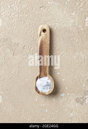 bicarbonate de soude dans une cuillère en bois sur fond de table beige, vue du dessus Banque D'Images