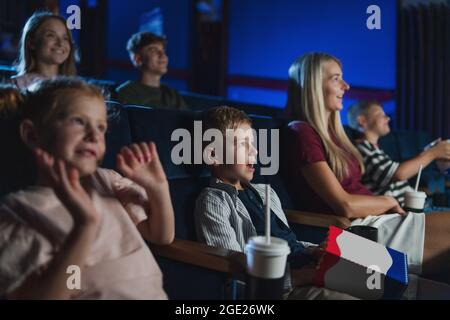 Mère avec de jeunes enfants heureux dans le cinéma, regarder le film. Banque D'Images