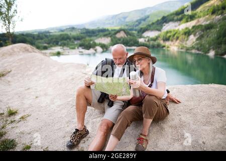 Couple senior heureux en randonnée sur les vacances d'été, à l'aide de la carte. Banque D'Images