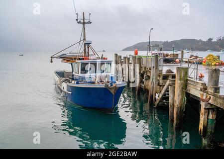 Un bateau de pêche amarré au quai flotte sur la mer fixe, attendant le prochain voyage sur l'océan Banque D'Images