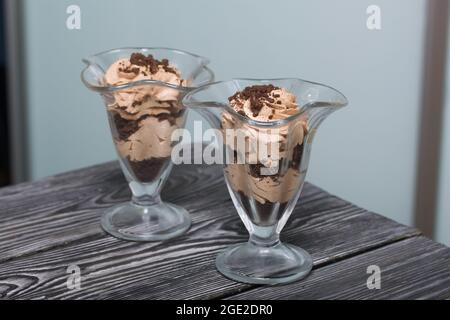 Dessert avec crème et chapelure de biscuits. Se tient sur des planches de pin. Gros plan. Banque D'Images