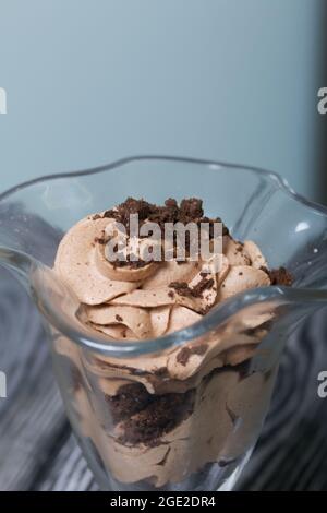 Dessert avec crème et chapelure de biscuits. Se tient sur des planches de pin. Gros plan. Banque D'Images