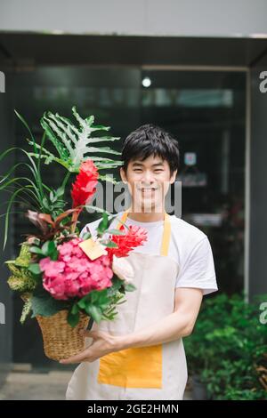 Fleuriste masculin tenant un bouquet de fleurs sur le lieu de travail Banque D'Images