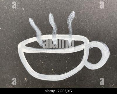 Gros plan d'une tasse blanche d'une icône de café chaud sur une surface sombre Banque D'Images