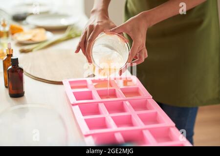 Image rapprochée d'une femme qui verse du savon fondu avec des huiles essentielles sous forme de plastique Banque D'Images