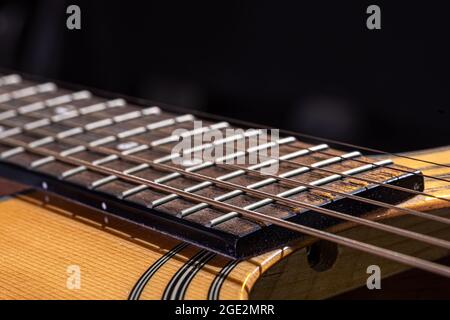 Partie d'une guitare acoustique, fretboard de guitare avec cordes sur fond noir. Banque D'Images