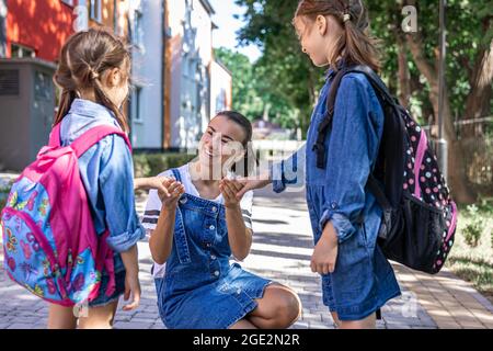 Une jeune femme soutient moralement les filles qui tiennent la main encourage les enfants, accompagne les élèves à l'école. Banque D'Images