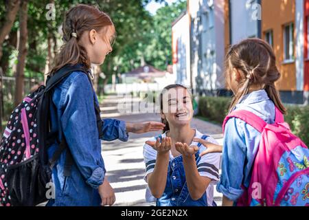 Une jeune femme soutient moralement les filles qui tiennent la main encourage les enfants, accompagne les élèves à l'école. Banque D'Images