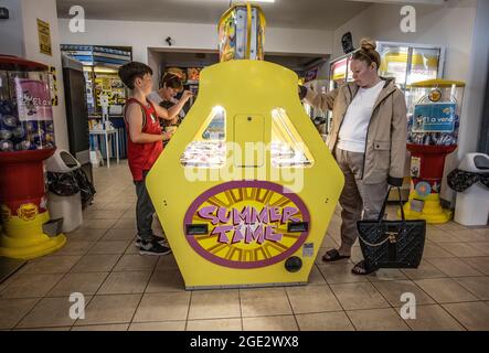 Les gens qui apprécient les arcades d'amusement jouant aux jeux de machines à sous à, Goodrington Sands, station balnéaire de Paignton sur la côte sud du Devon, Royaume-Uni Banque D'Images