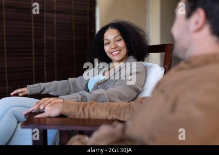 Joyeux couple varié dans le salon souriant et tenant les mains Banque D'Images