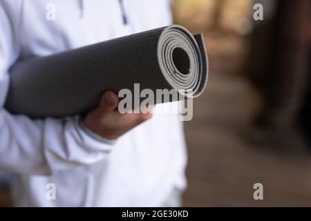 Gros plan de l'homme caucasien tenant un tapis de yoga avant de pratiquer le yoga Banque D'Images