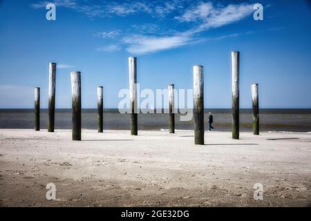 Pays-Bas, Petten, Plage. Mer du Nord. Palendorp. Œuvres d'art avec poteaux en bois. Homme, bateau à voile. Banque D'Images