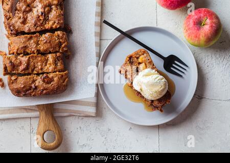 Pain aux pommes avec une cuillère de crème glacée et de sirop d'érable sur une assiette grise. Tarte aux fruits d'automne, fond gris, vue du dessus. Banque D'Images