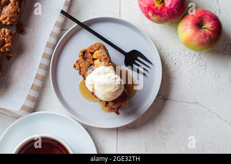 Pain aux pommes avec une cuillère de crème glacée et de sirop d'érable sur une assiette grise. Tarte aux fruits d'automne, fond gris, vue du dessus. Banque D'Images