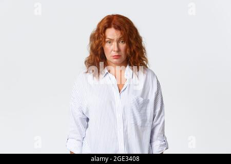 Sceptique et confus, fatiguée redhead moyenne-âge employée, entrepreneur regardant épuisé et perplexe, ne peut pas comprendre ce qui se passe Banque D'Images