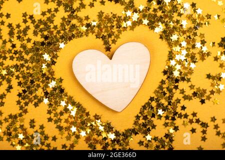 Coeur en bois en étoiles dorées sur fond jaune..Saint Valentin 14 février, journée mondiale du coeur 29 septembre... Banque D'Images