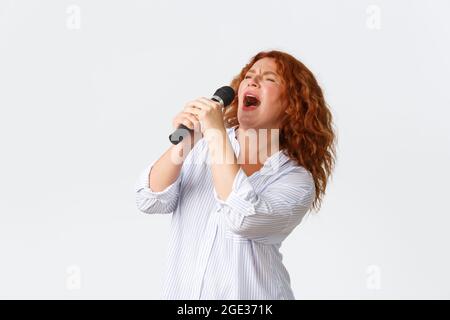 Emotions, style de vie et loisirs. Artiste féminine passionnée et insouciante, femme d'âge moyen chantant une chanson dans le microphone, chanteuse Banque D'Images