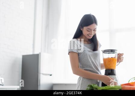 gaie femme asiatique préparant un smoothie aux légumes pour le petit déjeuner dans la cuisine Banque D'Images