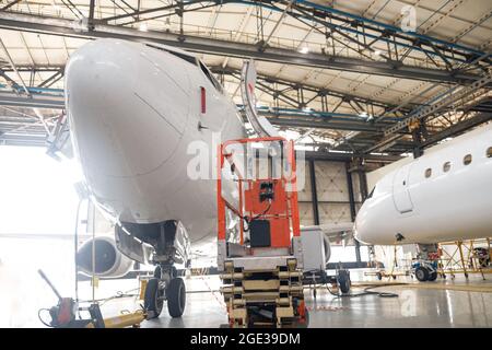 Avion de passagers moderne sur l'entretien de réparation vérifier dans le hangar de l'aéroport à l'intérieur Banque D'Images