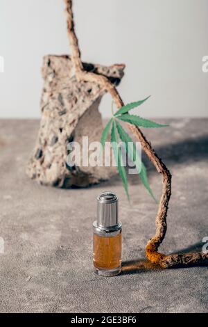 Bouteille en verre avec huile de CBD, teinture de THC et feuille de chanvre sur fond de marbre gris. Minimalisme, naturel. Cosmétiques à l'huile CBD. Banque D'Images