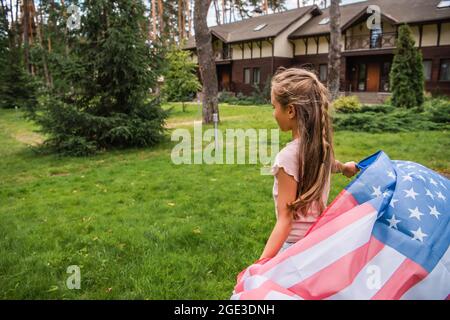 Fille portant le drapeau américain sur la pelouse à l'extérieur Banque D'Images