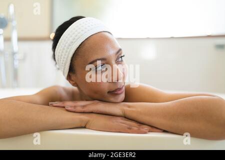 Femme de race mixte souriante dans la salle de bains se détendant dans la salle de bains Banque D'Images