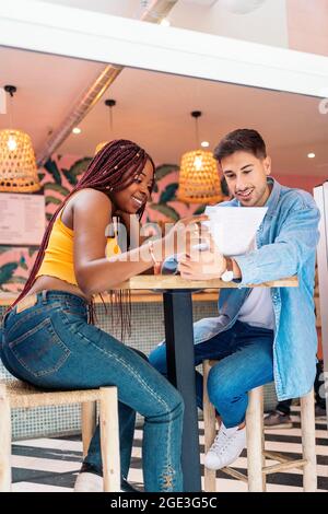 Amis multiculturels assis dans un restaurant et lisant le menu ensemble. Banque D'Images