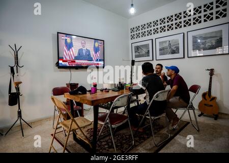 Kuala Lumpur, Malaisie. 16 août 2021. Des gens regardent le discours du Premier ministre Muhyiddin Yassin sur un écran de télévision à Kuala Lumpur.le Premier ministre malaisien Muhyiddin Yassin a annoncé sa démission lors d'une conférence de presse officielle au Cabinet du Premier ministre (PMO) à Putrajaya. (Photo de Syairy Redzuan/SOPA Images/Sipa USA) crédit: SIPA USA/Alay Live News Banque D'Images