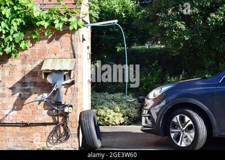 Voiture électrique rurale point de recharge d'une voiture entièrement électrique sur une allée rurale avec logement de charge de voiture sur mesure, point de charge de voiture électrique EV Banque D'Images