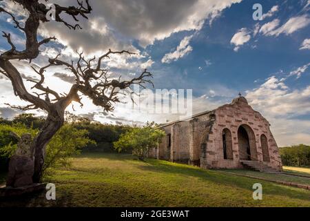 Église catholique de forme particulière avec un ciel spectaculaire et un arbre sec à Cerro Colorado, Cordoue, Argentine Banque D'Images