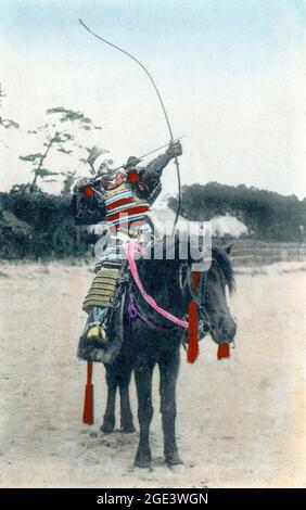 Ancienne carte postale japonaise de couleur main, vers 1900, d'un Archer monté à cheval dans une armure samouraï tirant un arc, (yumi) et une flèche. Banque D'Images