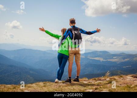 Couple aimant de randonneurs admirez la vue sur les montagnes carpathes. Les touristes heureux se sont enhardus au-dessus de Hoverla levant les bras. Voyager en été en Ukraine Banque D'Images