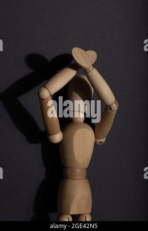 Supports de mannequin en bois avec mains levées sur fond gris. Protestation, concept d'attention. Espace de copie, lumière dure. Banque D'Images