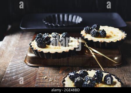 Mini-tartes fraîchement cuites aux mûres sur une table en bois. Banque D'Images